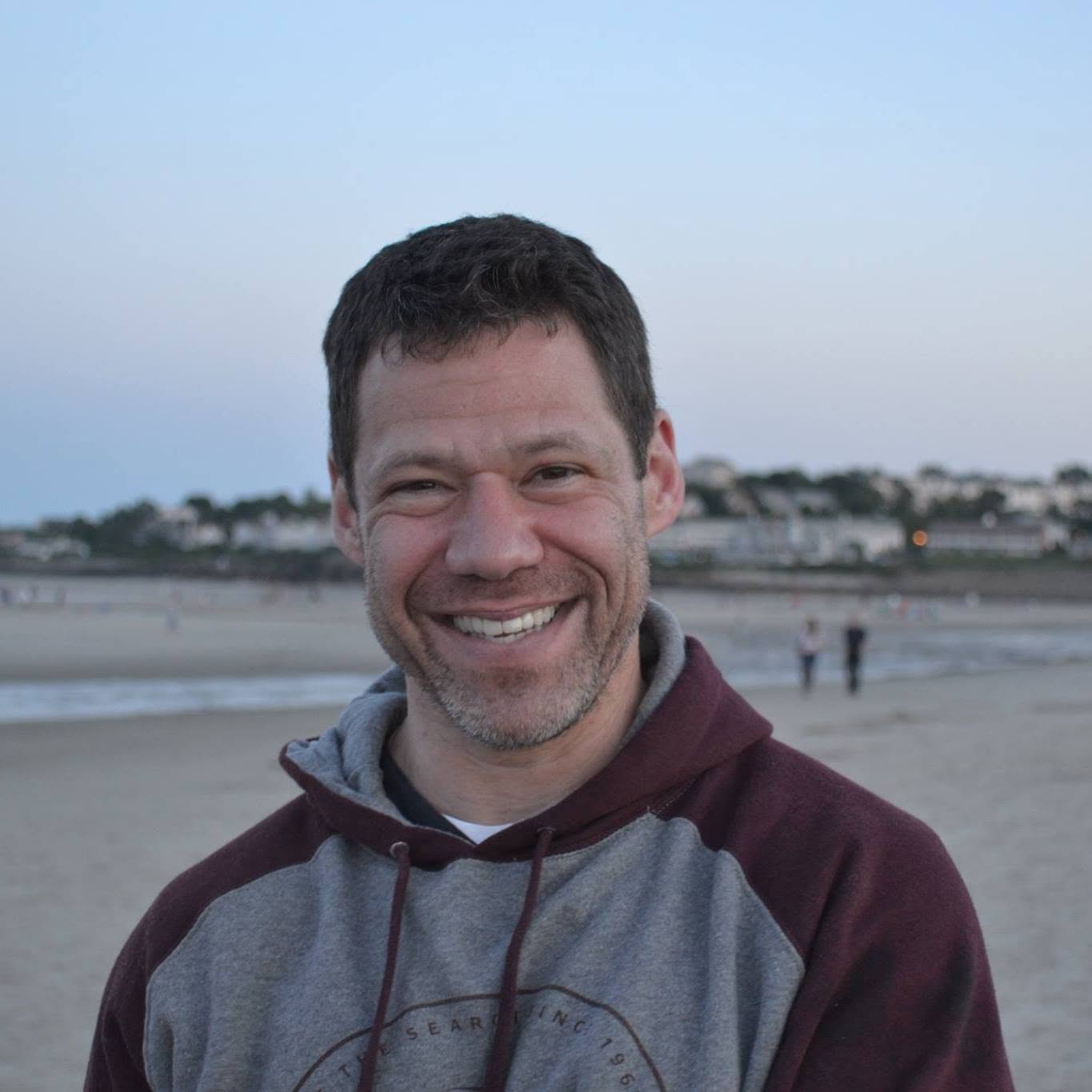 Kevin Maloney, founder of The Strength Room, smiling on the beach at dusk