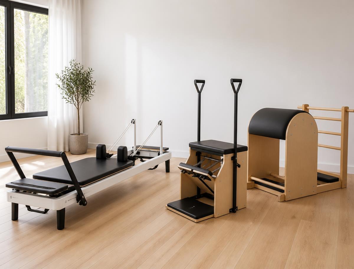 A reformer, Pilates chair and ladder barrel arranged together in a quiet corner of the studio