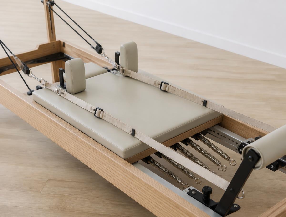 Close view of a reformer carriage, cream straps and coiled springs beneath the frame